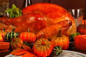 A Thanksgiving turkey with decorative mini-pumpkins in the foreground.
