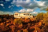 A motor home parked in the desert under a fantastic sky.