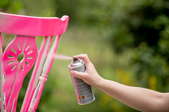 A chair being spray painted pink.