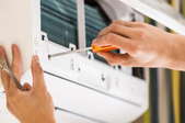 hands with screwdriver working on air conditioner