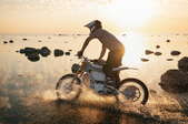 A man riding a dirt bike at sunset