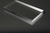 A small piece of plexiglass on a dark grey surface.