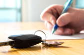 hands with pen and paper next to car keys