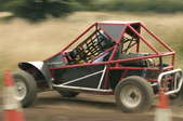 A dune buggy driving on a dirt track.