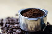 tin of ground coffee resting on top of coffee beans