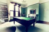 Pool table in a room with green walls and dark wood