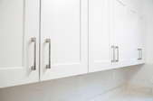 white painted veneer kitchen cabinets with metal hardware