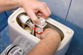 Reaching inside and open toilet tank to adjust components.