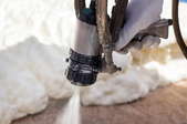 gloved hand spraying foam insulation