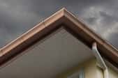 roof and gutter under heavy rain clouds