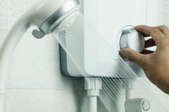 hand adjusting temperature on electric water heater in shower