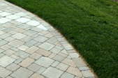 Grass borders a driveway made from pavers.