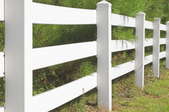 vinyl fence running between grass and bushes