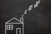 a chalkboard drawing of a house with dollar signs coming out the chimney
