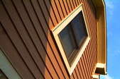 Looking up the side of a brown-sided house at its yellow eaves.