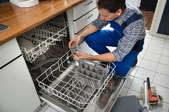A man removing the drain from a dishwasher.