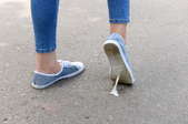A person walking in sneakers with a piece of chewing gum stuck to their shoe.
