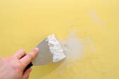 filling wall hole with putty knife and spackle