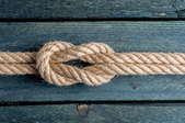 a square knot tied in a rope on wood