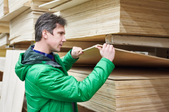 a man inspecting a stack of plywood