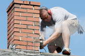 A worker performing maintenance on a brick chimney.