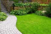 A landscaped space with a curved paver walkway and lush lawn.