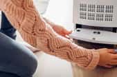 person in sweater opening the bottom of a dehumidifier