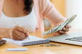 woman organizing money with notebook and computer