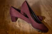 A pair of wine colored high heeled shoes made from suede.