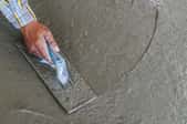 a hand smoothing out self leveling concrete