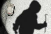 A motion sensor light shows the outline of a hooded figure with a crowbar.