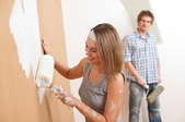A woman painting a wall white.