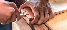 hands cutting corner joints in wood