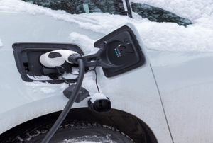 An electric car charging in the winter covered in snow.