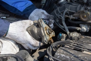gloved hands working with a car engine ignition system under the hood