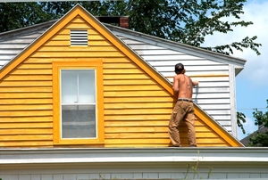 a triangular yellow house with a person standing on the roof