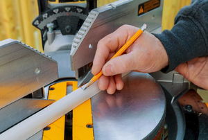 Man marking a cut point on a  piece of quarter round molding.