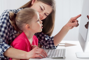 A mom an daughter use a computer.