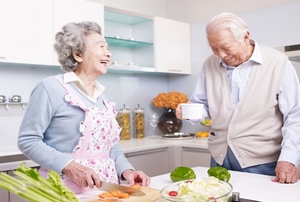 An elderly couple cooking in the kitchen together.