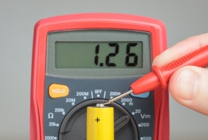 A multimeter testing the end of a battery.