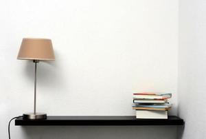 Floating bookshelf on a white wall with lamp and books
