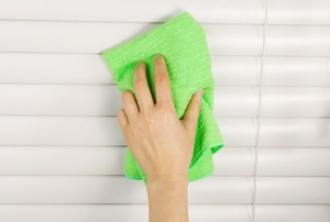 cleaning blinds with a green microfiber cloth