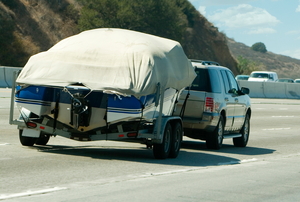 An SUV towing a covered boat.