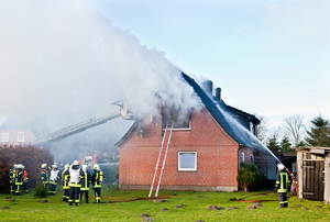 A house with firemen putting a fire out. 