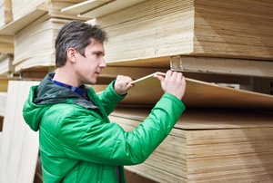 A man in a green jack choosing plywood.