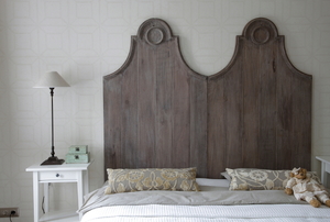A vintage wood headboard over a bed.