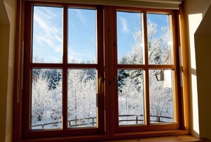 A window with wood casings looking out onto a snowy winter landscape.