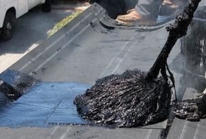 Person mopping hot tar onto a roof