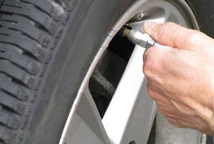 A car owner inflating a car tire with low air pressure.