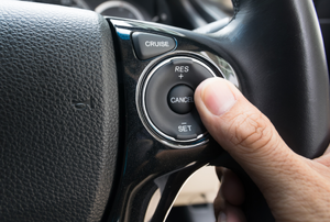 thumb on the button for cruise control in a car